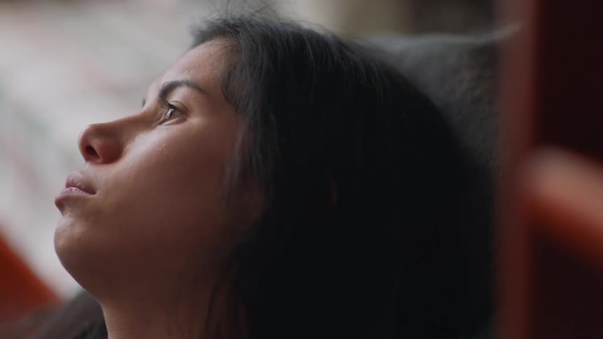 Young woman sighs while leaning her head against cushion near wooden ladder