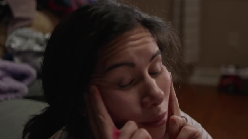 A sad woman rubs her face with her fingers