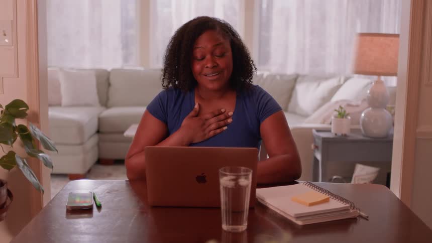 A woman sitting down at a laptop in a room