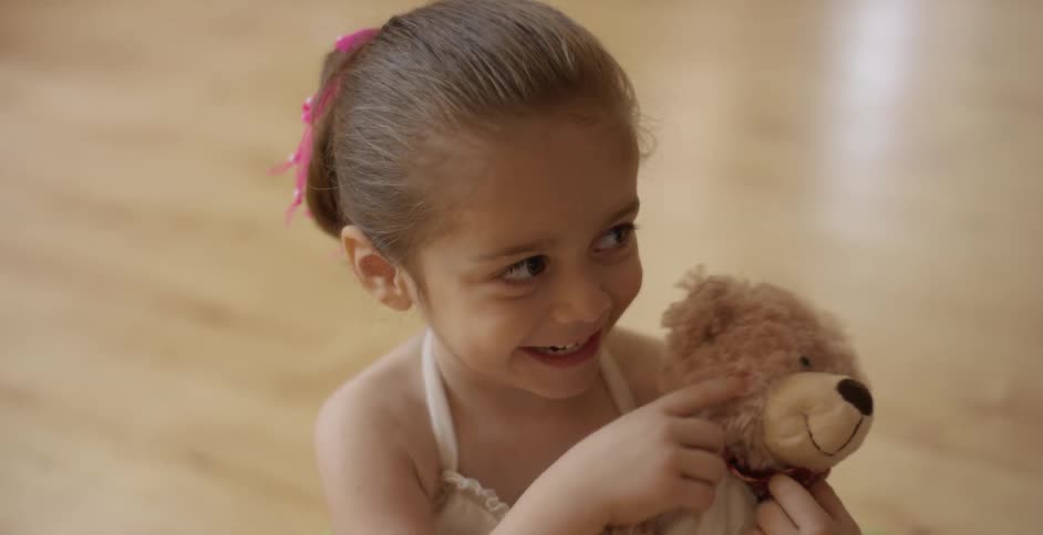 A young girl smiling and cuddling a teddy bear