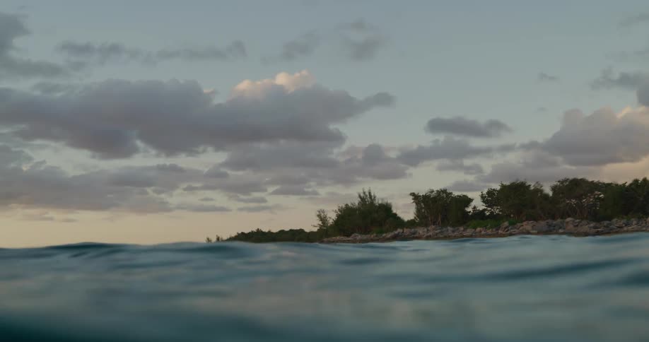 Waves roll across the surface of the ocean near the shore on a cloudy day
