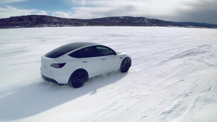 A white car drives through a snowy landscape