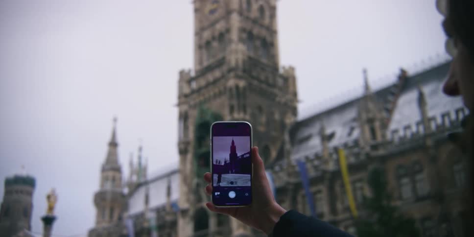Woman with an iphone photographing a cathedral on a cloudy day