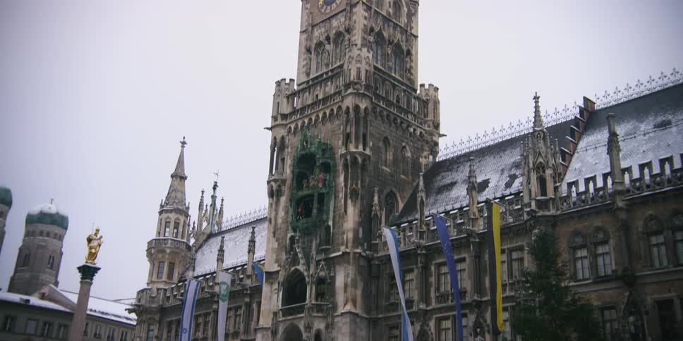 Exterior facade of a cathedral with flags on a cloudy and snowy day in winter