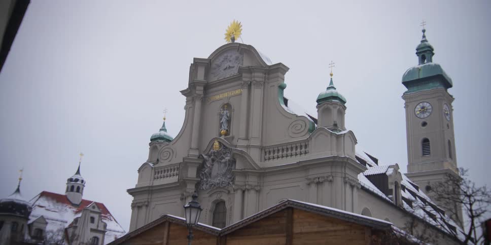 An adult walks down the street next to a church on a winter day