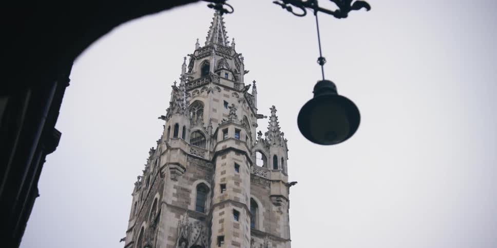 A gothicstyle tower with intricate designs against a cloudy sky
