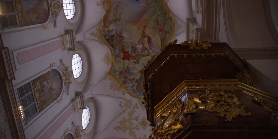 Gold decorated columnstands in cathedral under wall and ceiling art