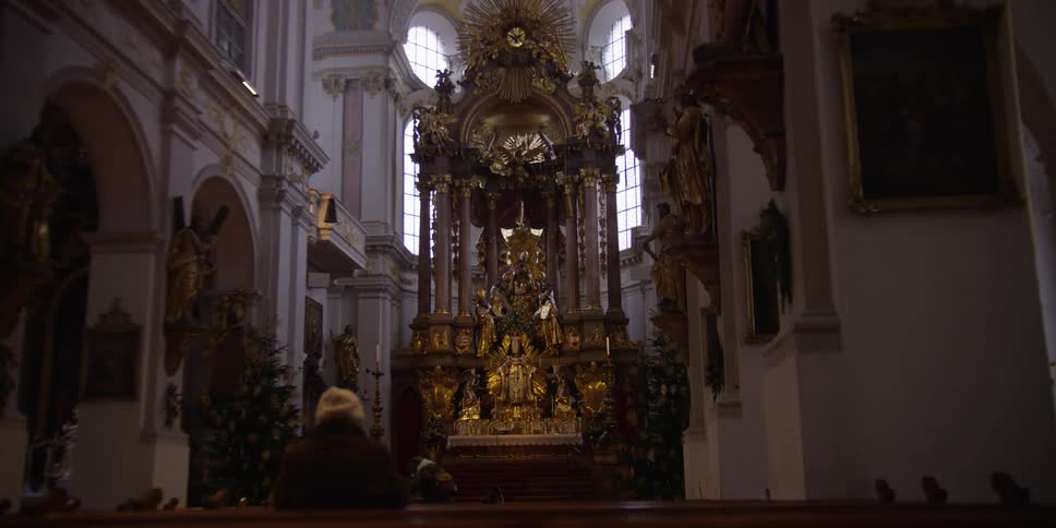 Interior of a church with wooden benches and an altar decorated in gold