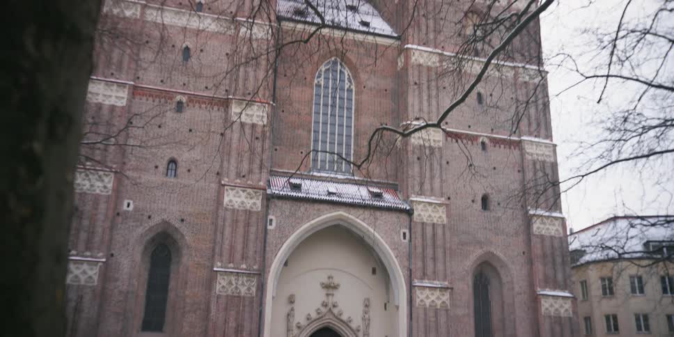 Facade of a cathedral on a cloudy winter day with people entering