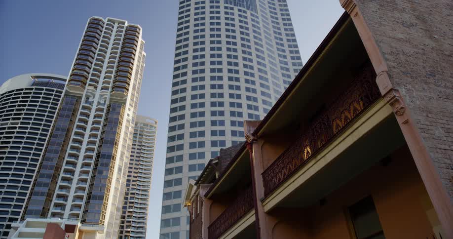 Skyscrapers tower over a small apartment building