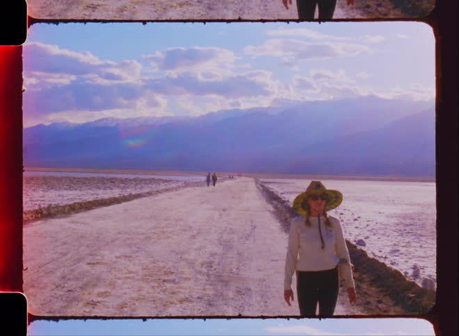 A woman walks down a dirt road towards the camera