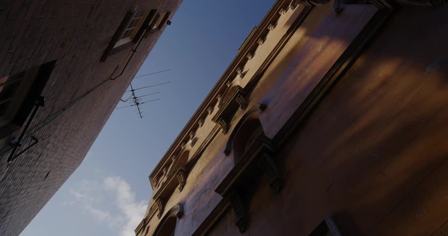 Clouds float over an antenna and two buildings on a sunny day