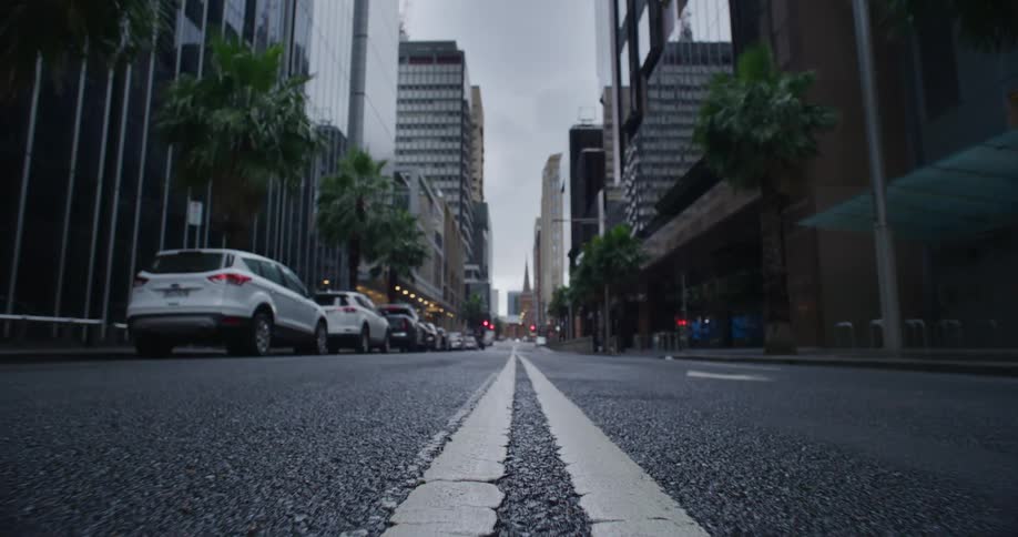 Groundlevel view of a city street with tall buildings and parked cars