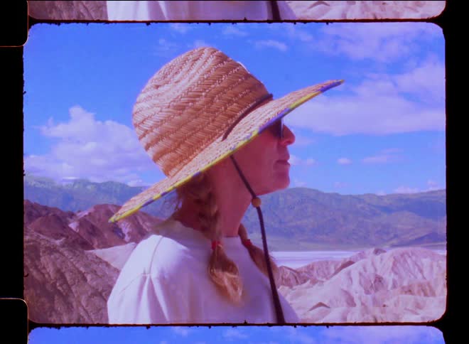 Side portrait of a blonde woman with braids and a sun hat in a natural environment by the canyons