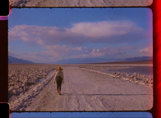 Woman walks along snow covered road bordered by icy water during winter
