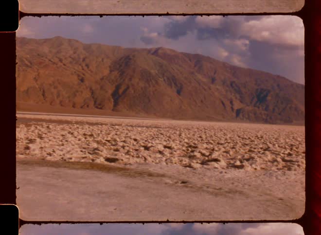 A desert region with large mountains and small pools of water scattered around