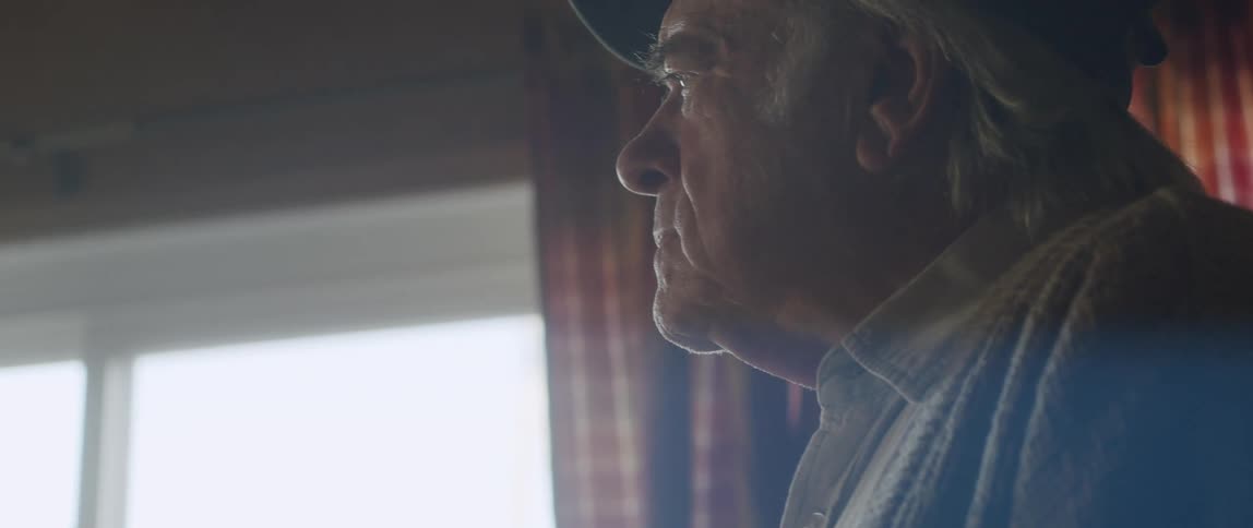 Elderly man paces back and forth thinking near the window