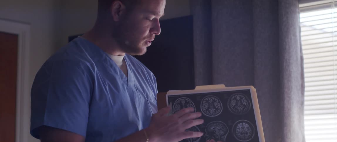 Doctor talking and explaining an xray that he is holding in one of his hands in a notebook