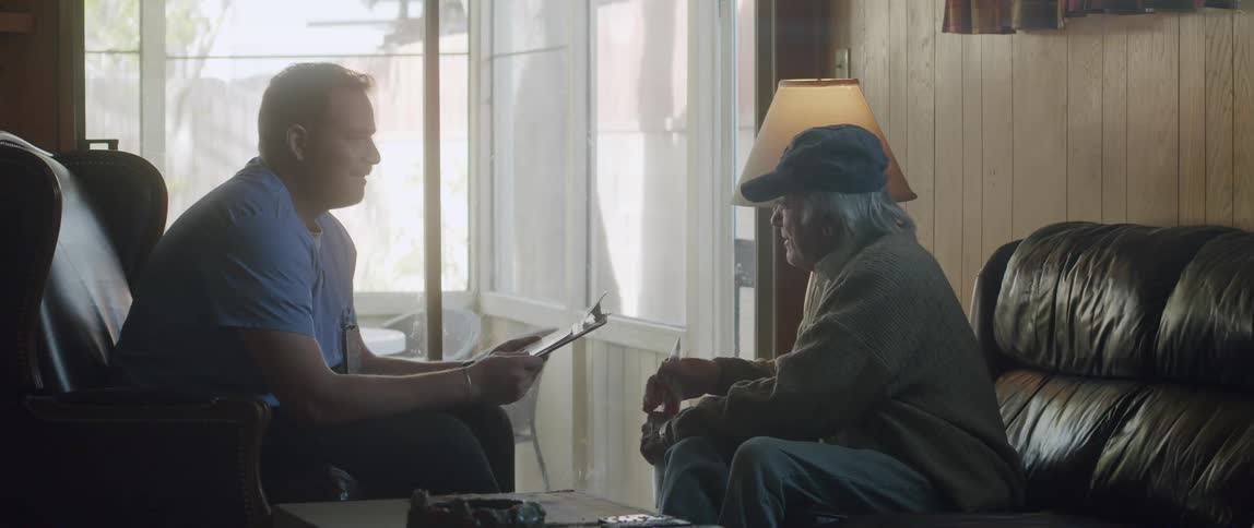 A male nurse talking to an elderly man at home