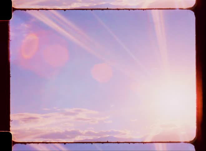 The sun sets over a mountain range on a partly cloudy day