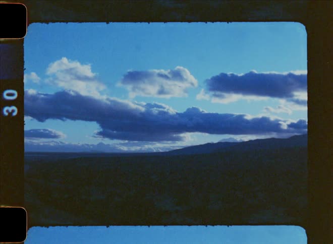 Landscape of a desert field with the silhouette of mountains on the horizon on a blue sky day with clouds