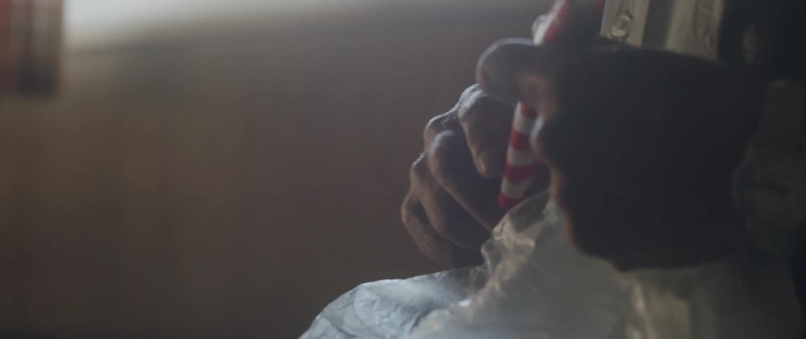 An old man walks in a room while twisting a small American flag