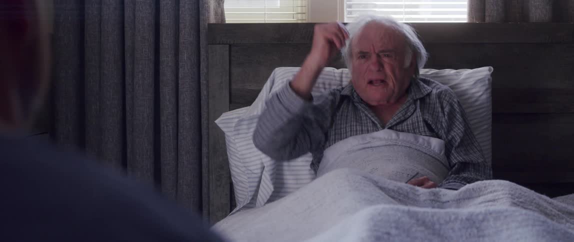 Elderly male patient complains to his nurse while sitting up in his bed at home