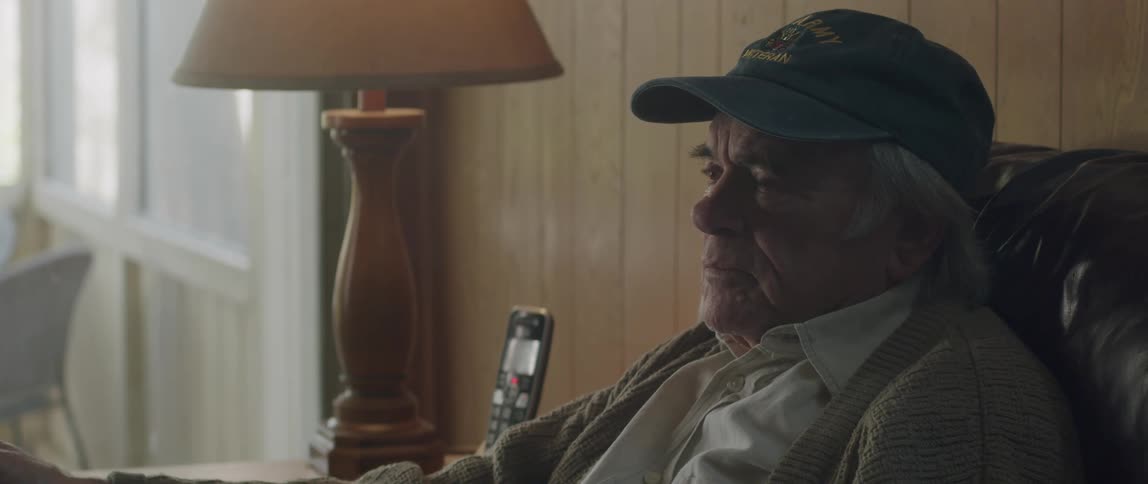 Side portrait of an elderly man with a bone hat sitting with a sad facial expression