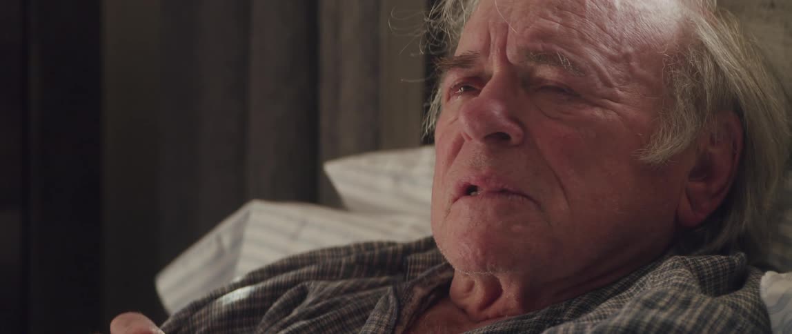Portrait of an elderly man lying in bed and his eyes watering with a sad facial expression while talking