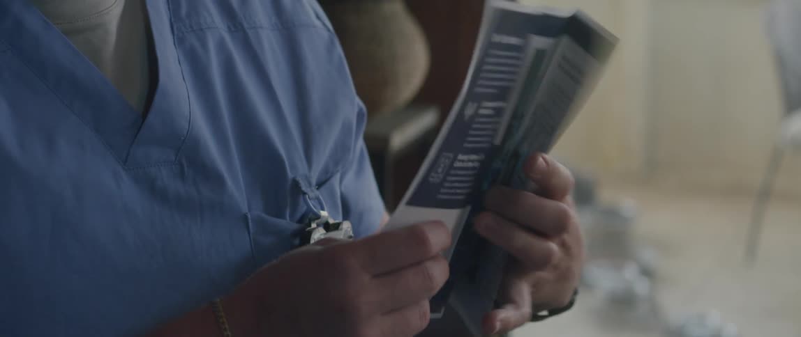 A male doctor taps to a medical pamphlet and opens it