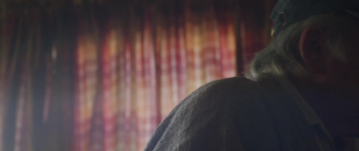Portrait of an elderly man adjusting his veteran hat while holding a small American flag