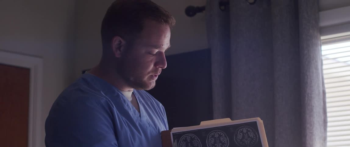 Doctor standing talking while holding a clipboard with a brain xray