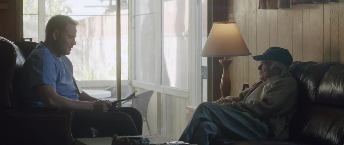 Two men sit in a living room and talk