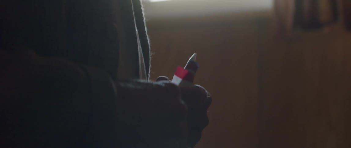 Elderly man holding a small US flag in his hands while indoors