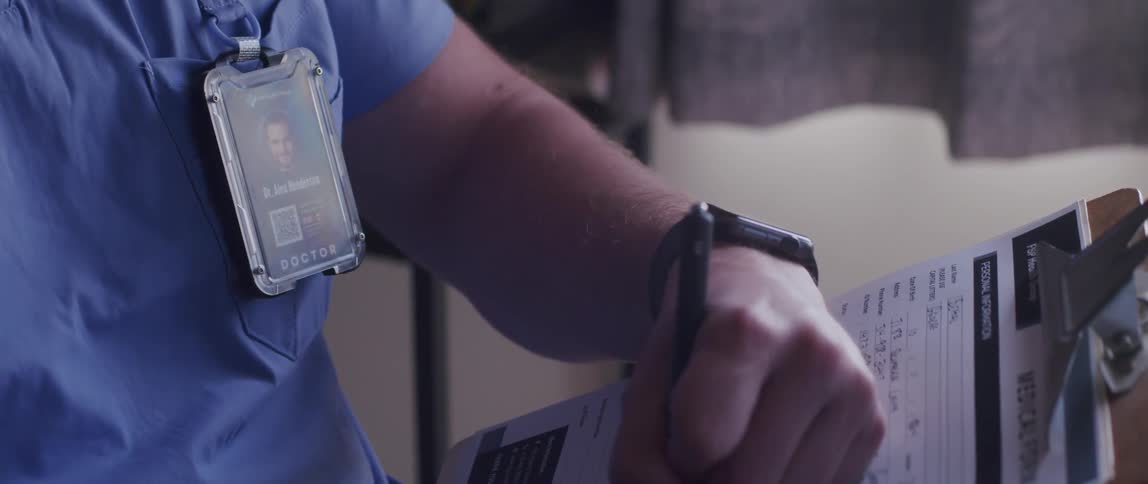 Hands of a doctor making notes on a clipboard in a medical record