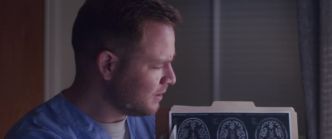 The face of a nurse who is pointing to a clipboard with drawings and speaking