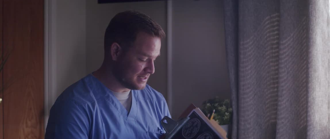 Smiling doctor talking and holding a clipboard and then standing up