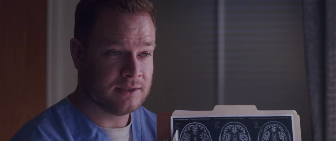 Medical professional refers to pictures of brain scan attached to clipboard while talking
