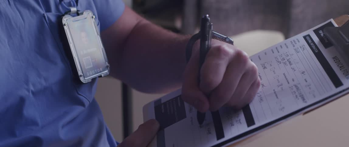 A male nurse takes notes on a clipboard