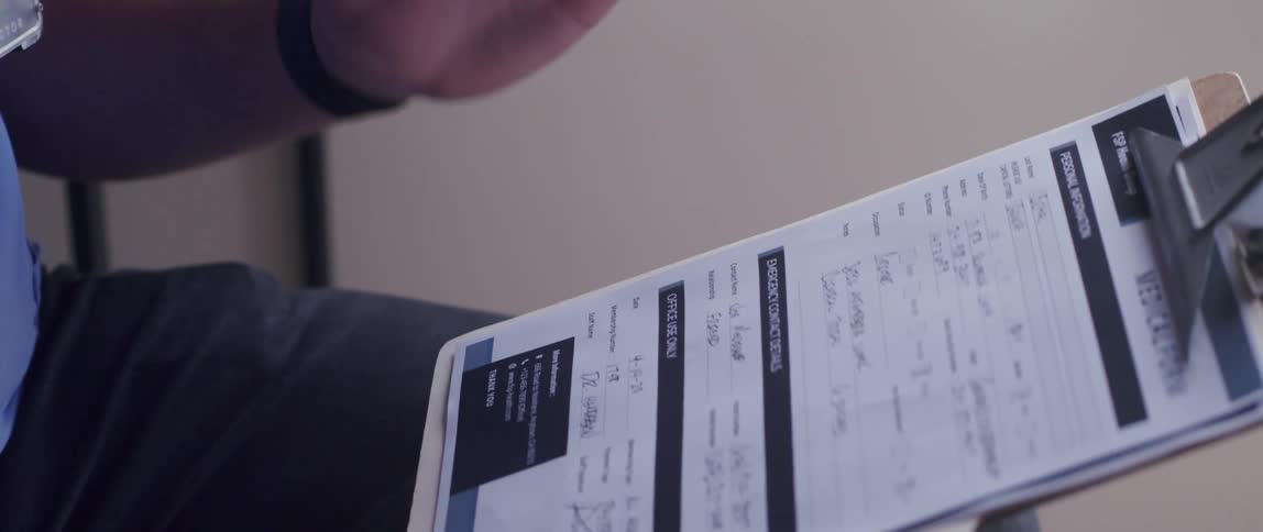 A healthcare worker holds a clipboard and gestures