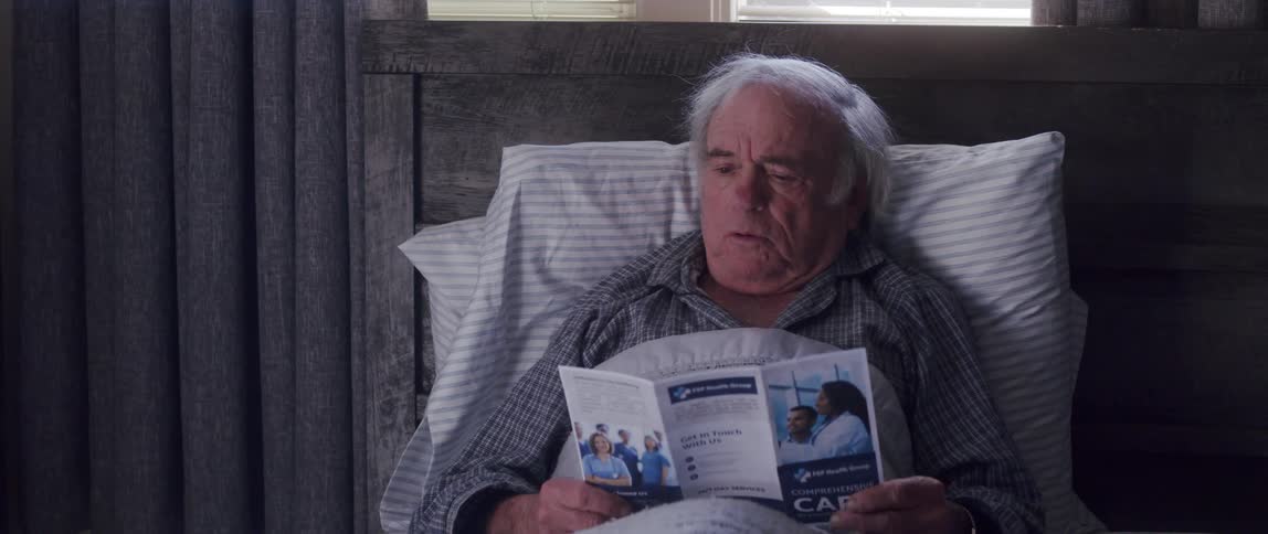 Elderly man lying in bed and with an upset facial expression while talking