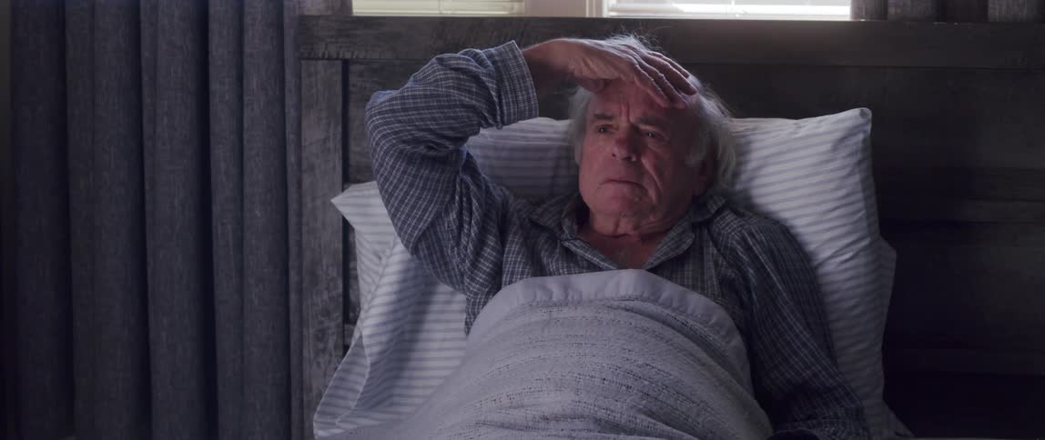 Elderly man resting in bed receives bad news