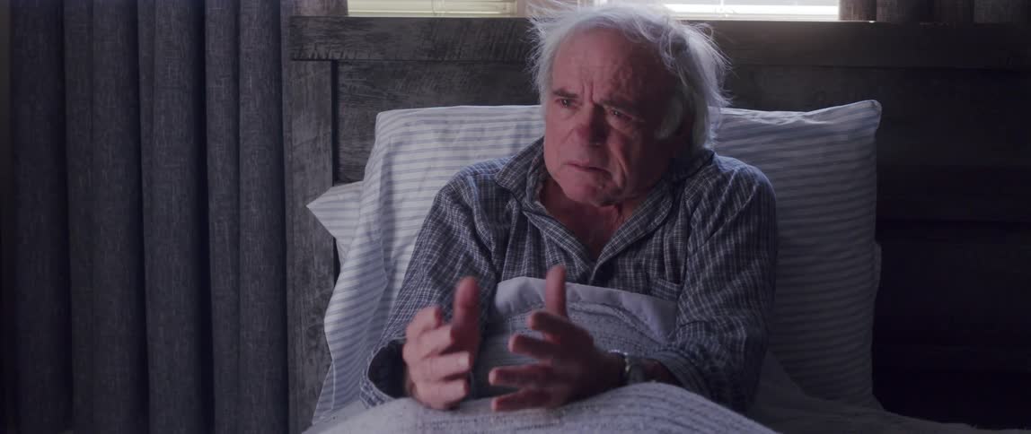 A clip of a sad old man on the bed