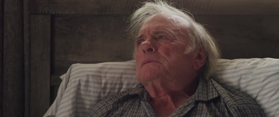 Portrait of an elderly man lying in bed breathing deeply with a facial expression of denial and sadness