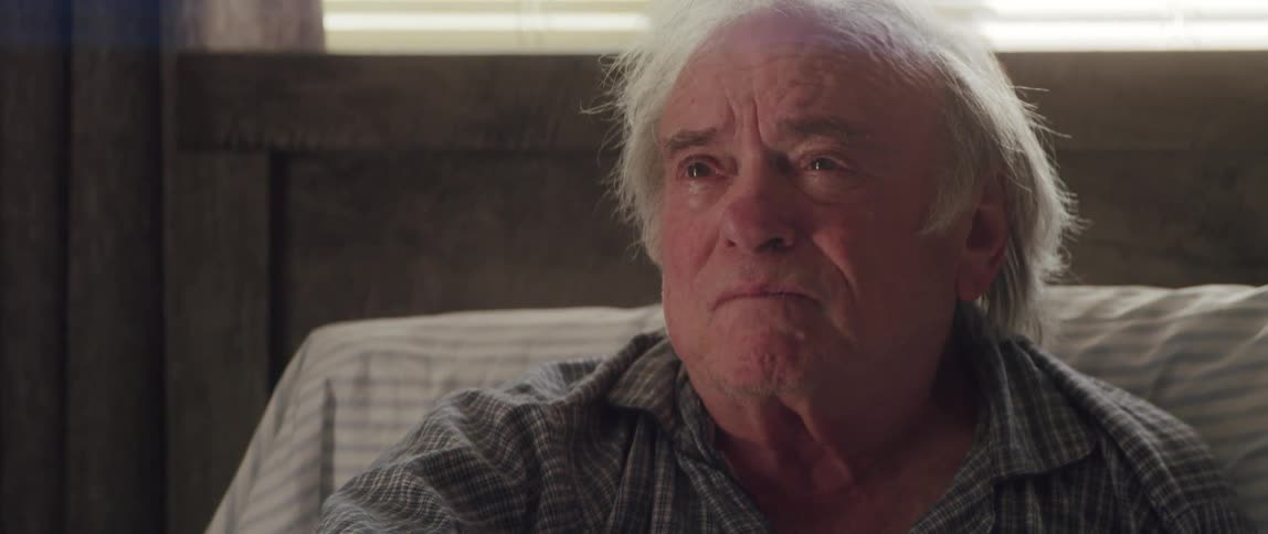 Elderly man sitting on the bed with a facial expression of sadness and discouragement greeting another person with his hands