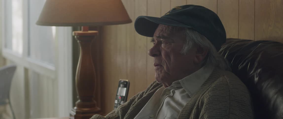 Elderly man sitting on a leather sofa with a sad facial expression