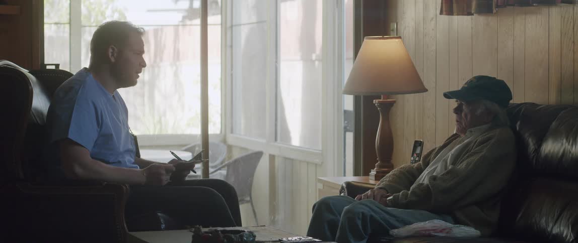Doctor and an elderly patient both sitting and talking inside a room