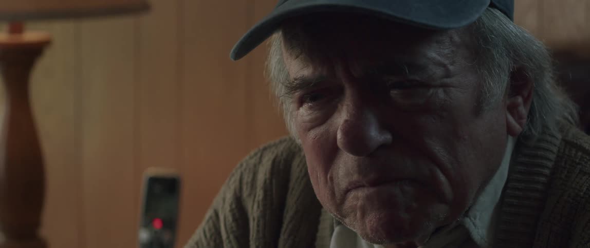 Portrait of an elderly man with a cap talking and with a sad facial expression