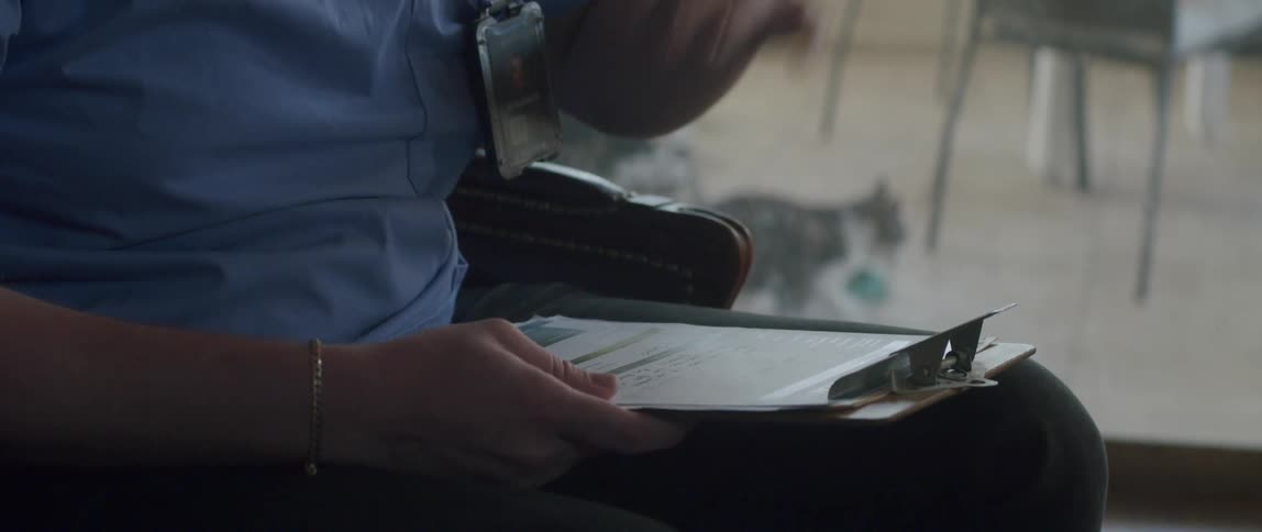 A healthcare worker with a clipboard gestures with his hands