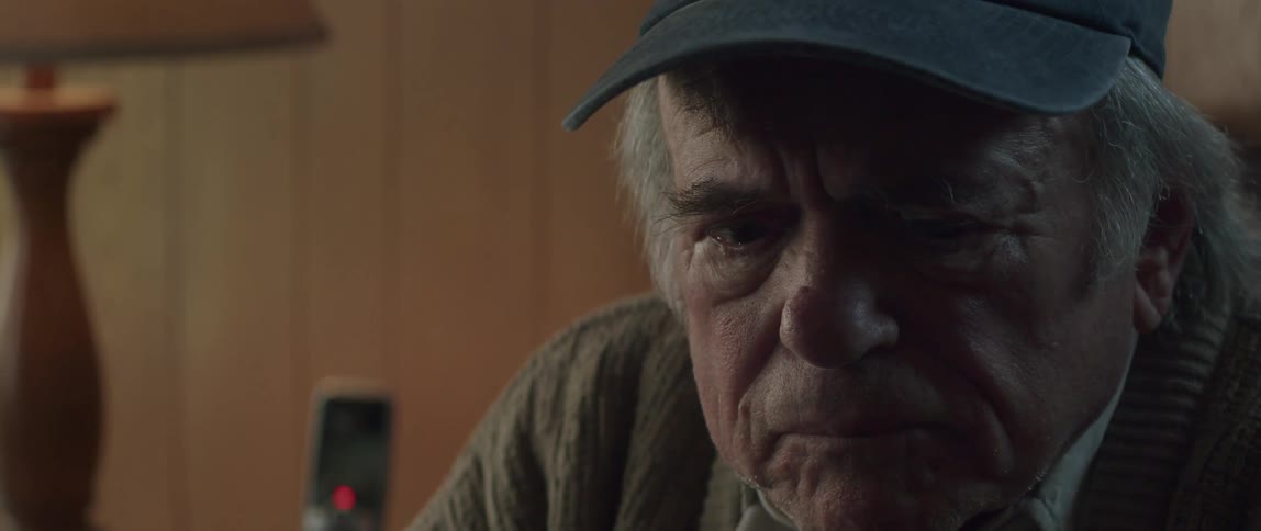 An elderly man wearing a hat seems upset while hes conversing